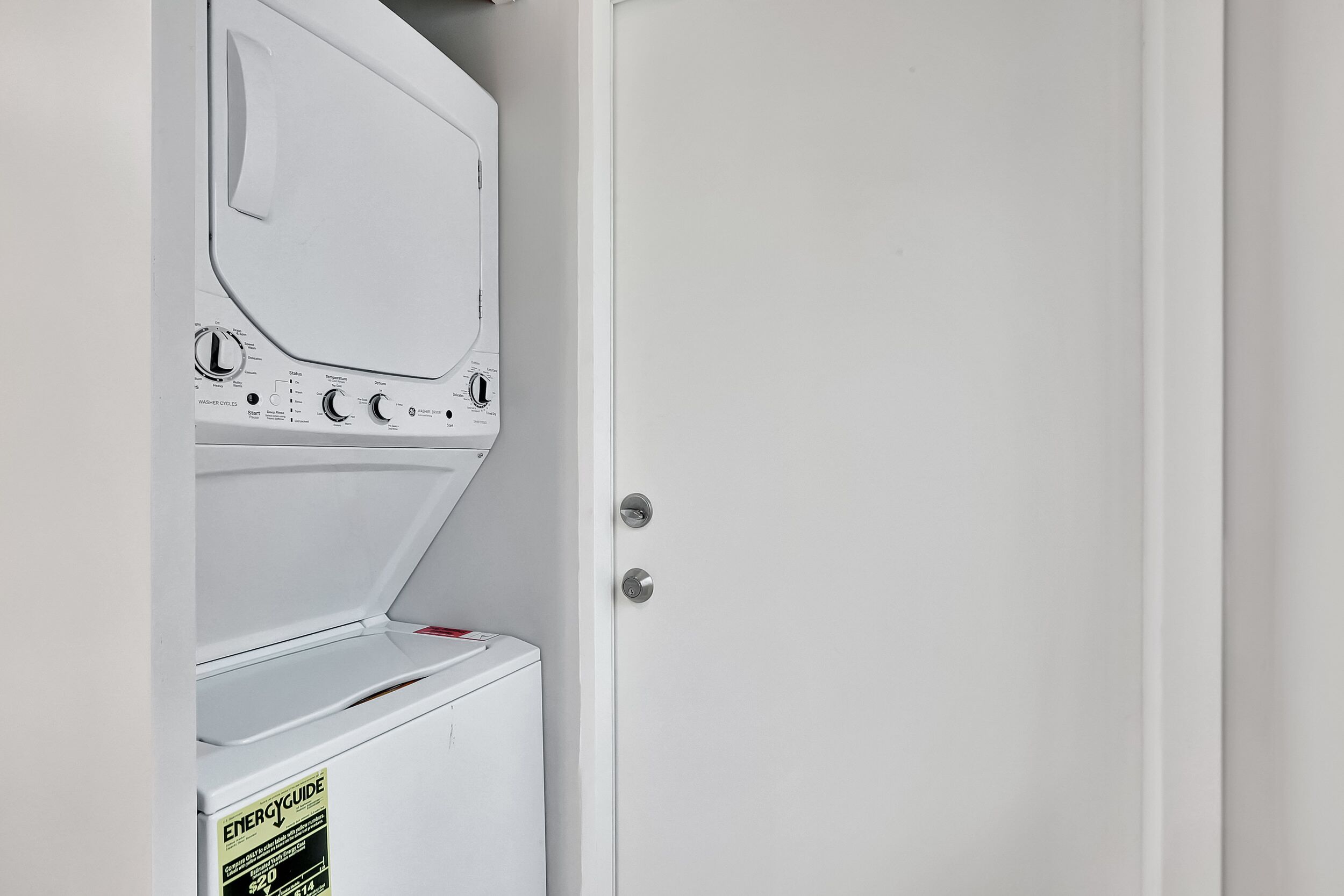 A white wall with a door and a washing machine.