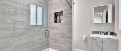 Une salle de bain moderne avec une douche à parois de verre, une baignoire blanche et un meuble-lavabo avec un miroir et un évier.