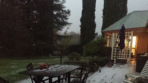 A patio with a wooden table and chairs, surrounded by snow-covered ground. - Burradoo Loft with king size bed. 
Close to Southern Highlands wineries. (Burradoo)
