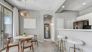 A modern kitchen with white cabinets, a stainless steel refrigerator, and a bar area with white stools. - Cozy 2 Bed, 2 Bath in Grayhawk (Scottsdale)