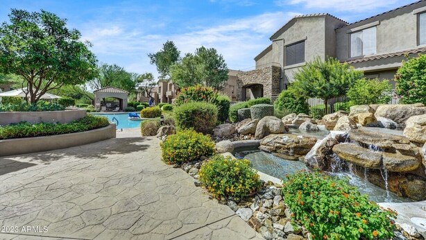 A landscaped outdoor area with a swimming pool, a small waterfall, and a gazebo. - Cozy 2 Bed, 2 Bath in Grayhawk (Scottsdale)