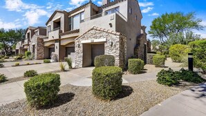 A modern two-story house with a stone facade, a garage, and a well-maintained garden with various shrubs and a gravel driveway. - Cozy 2 Bed, 2 Bath in Grayhawk (Scottsdale)