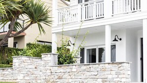 Une maison à deux étages avec un mur de soutènement en pierre, un balcon et une pelouse bien entretenue.