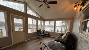 A spacious room with a large window overlooking a body of water, a ceiling fan, and a dining area with a table and chairs. - Beautiful Riverfront Home near Celebrations. Excellent eagle viewing! (La Crosse)
