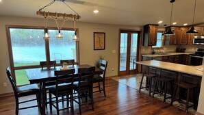 A spacious kitchen with wooden cabinets, a large island, and a view of a lake. - Beautiful Riverfront Home near Celebrations. Excellent eagle viewing! (La Crosse)