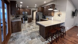 A modern kitchen with granite countertops, stainless steel appliances, and wooden cabinets. - Beautiful Riverfront Home near Celebrations. Excellent eagle viewing! (La Crosse)