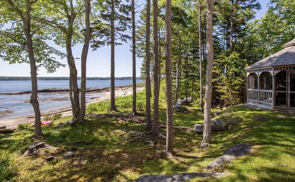 Un pabellón de madera con vistas a un lago y una playa.