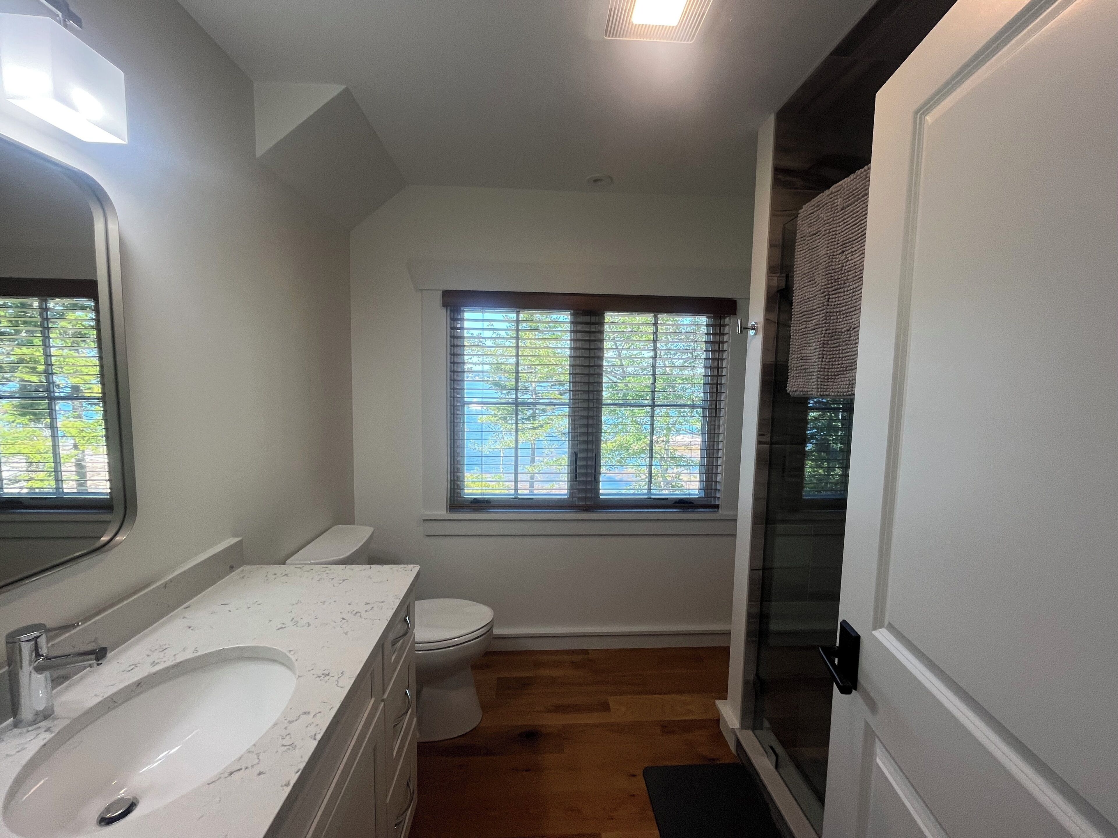 A bathroom with a white sink, a toilet, and a window with blinds.