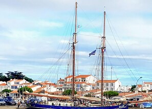 A large sailing ship docked at a harbor with buildings in the background.