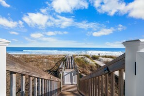 A wooden boardwalk leading to a beach with a clear sky.