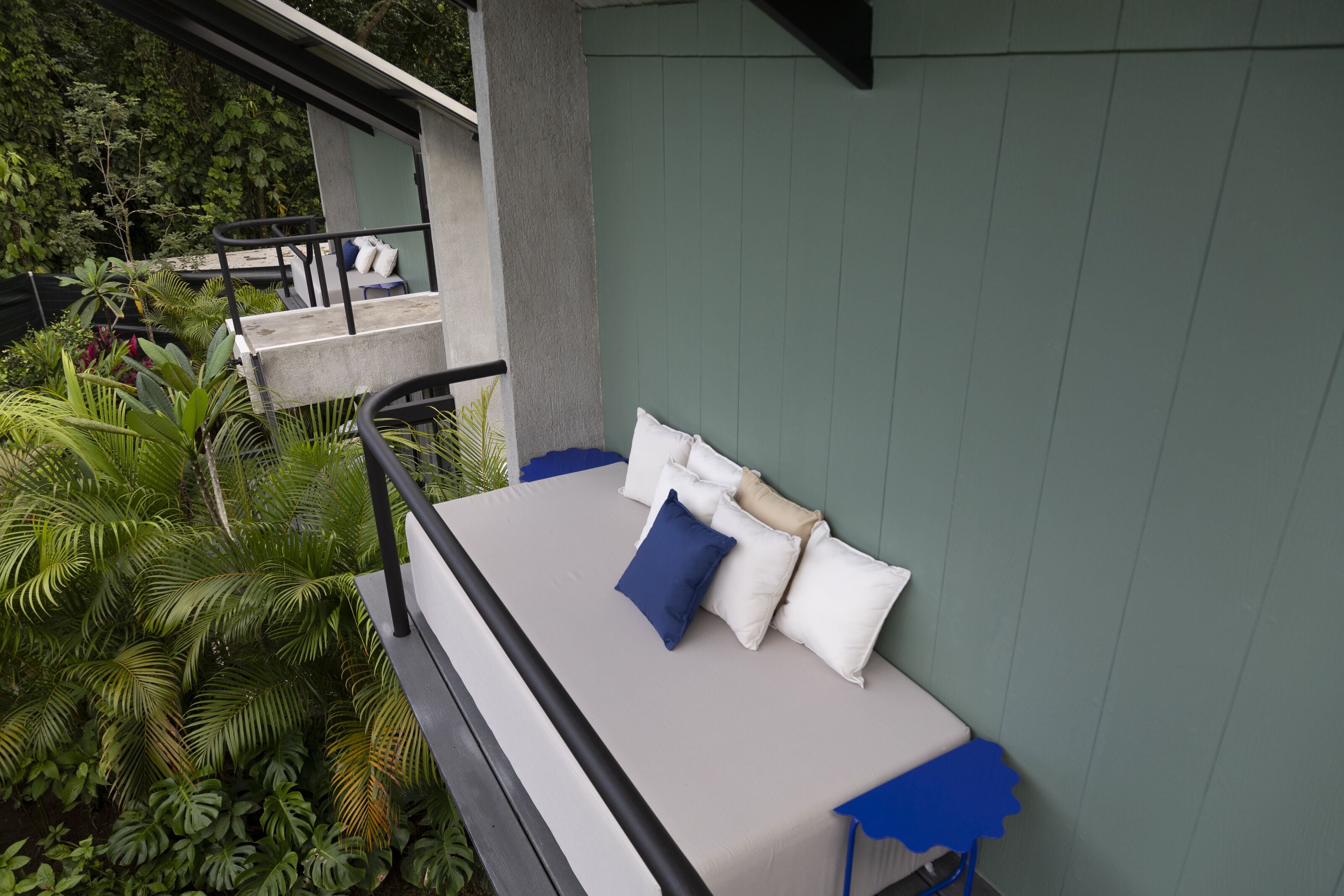 A bed with white and blue pillows, a grey mattress, and a blue blanket.