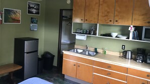 Una cocina compacta con armarios de madera, un lavamanos, un refrigerador y un microondas.