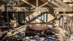 A covered outdoor area with a hot tub, stone benches, and a wooden deck. - Mountain Rustic Perfection in Prime Locale (Park City)