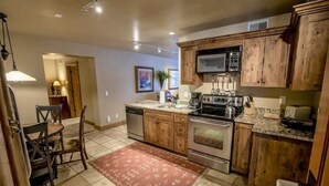 A kitchen with wooden cabinets, a microwave, stove, and a coffee maker. - Mountain Rustic Perfection in Prime Locale (Park City)
