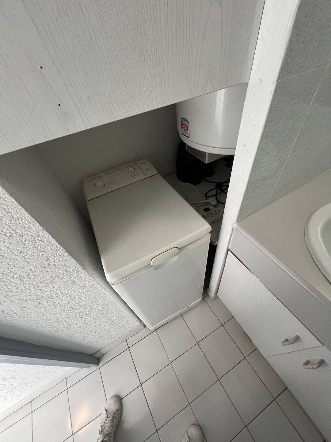 A compact bathroom with a toilet, a small washing machine, and a sink.