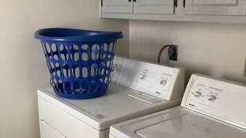 A laundry area with a blue laundry basket on a washing machine and a dryer.