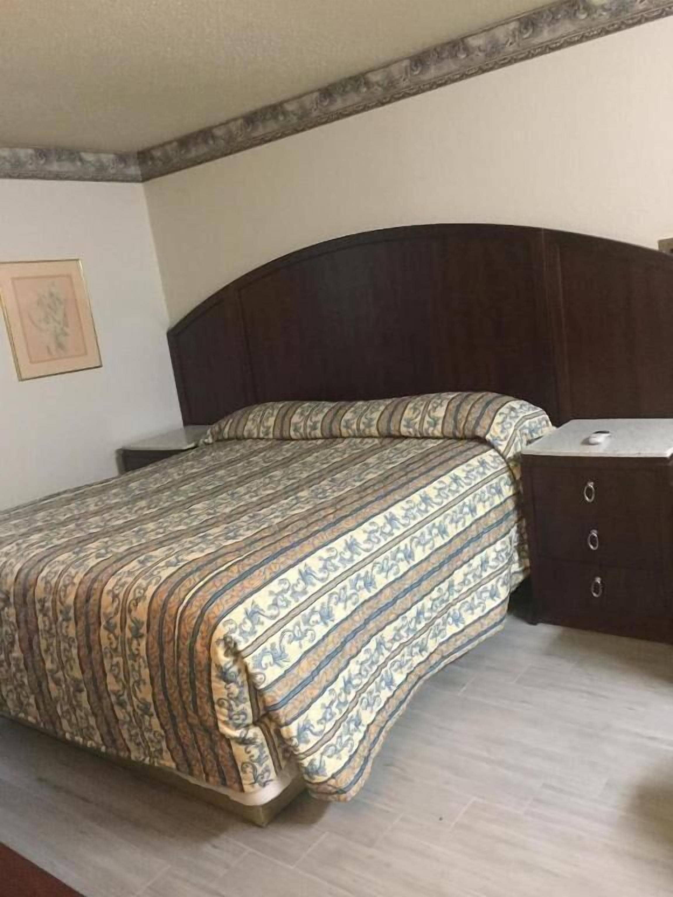 Un dormitorio con cama, cómoda y un cuadro en la pared.