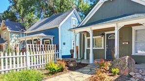 A residential property with a stone pathway, a white picket fence, and a porch with a covered entryway.