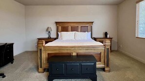 Une chambre à coucher comprenant un lit, des tables de chevet, une commode, un ventilateur de plafond et une fenêtre.