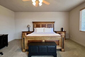 A bedroom with a bed, nightstands, a dresser, a ceiling fan, and a window.