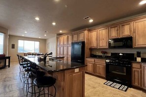A modern kitchen with wooden cabinets, a black refrigerator, a stove, and a microwave.