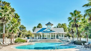 A pool area with a building, palm trees, and a clear blue sky.