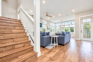 A modern interior with a wooden staircase, a sectional sofa, and a dining area.