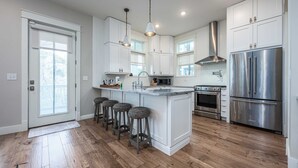 A modern kitchen with white cabinets, stainless steel appliances, and a central island with bar stools.