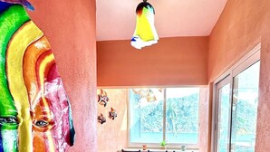 A narrow hallway with a tiled floor, a ceiling fan, and a window with a view of a mountainous landscape.