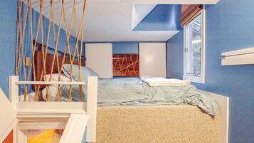 A bedroom with a bed, a hanging chair, a window, and a ceiling design.