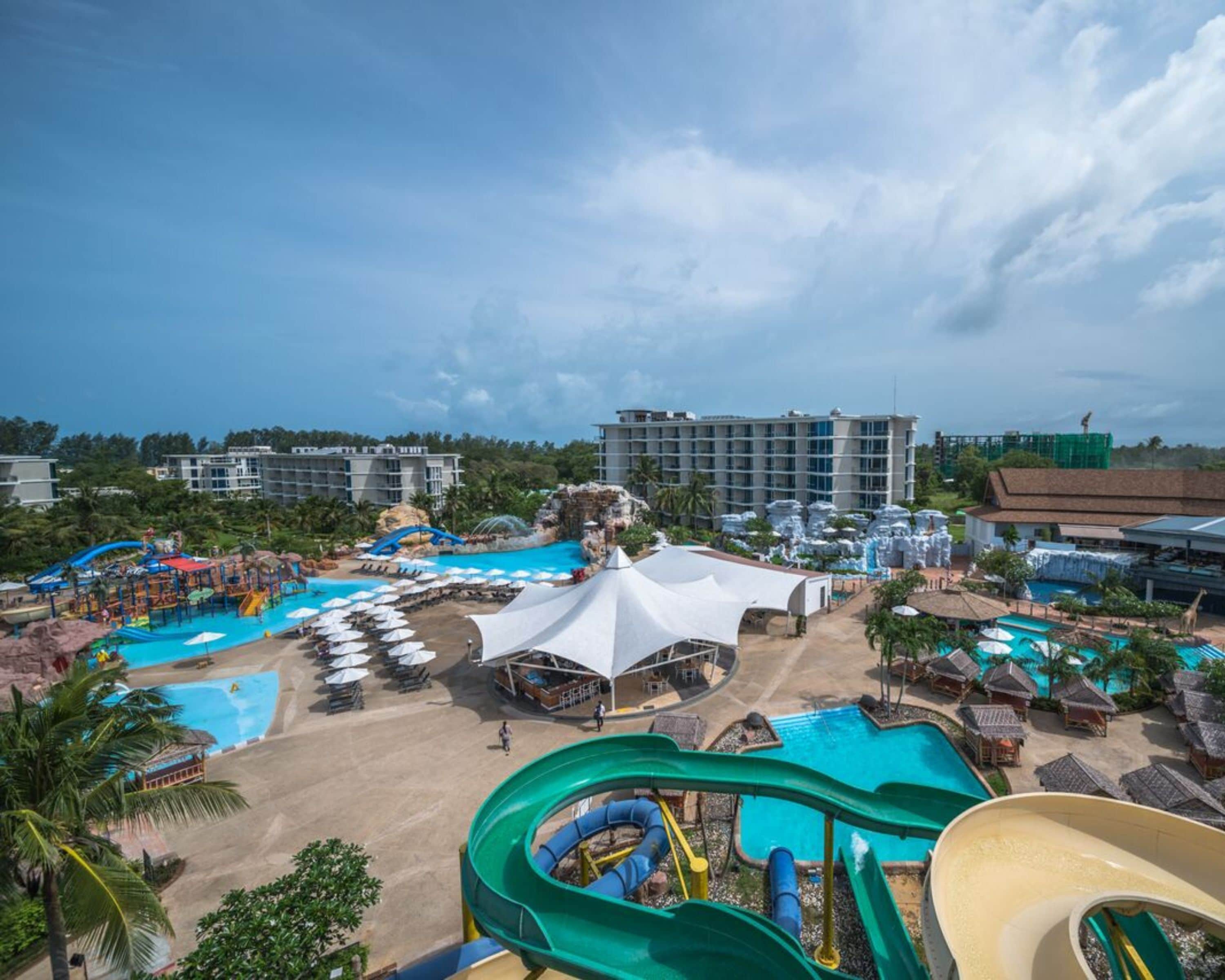 A resort with multiple swimming pools, water slides, and beach umbrellas.