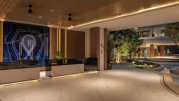 A modern lobby with a marble floor, wooden ceiling, and a reception desk with a blue abstract design.