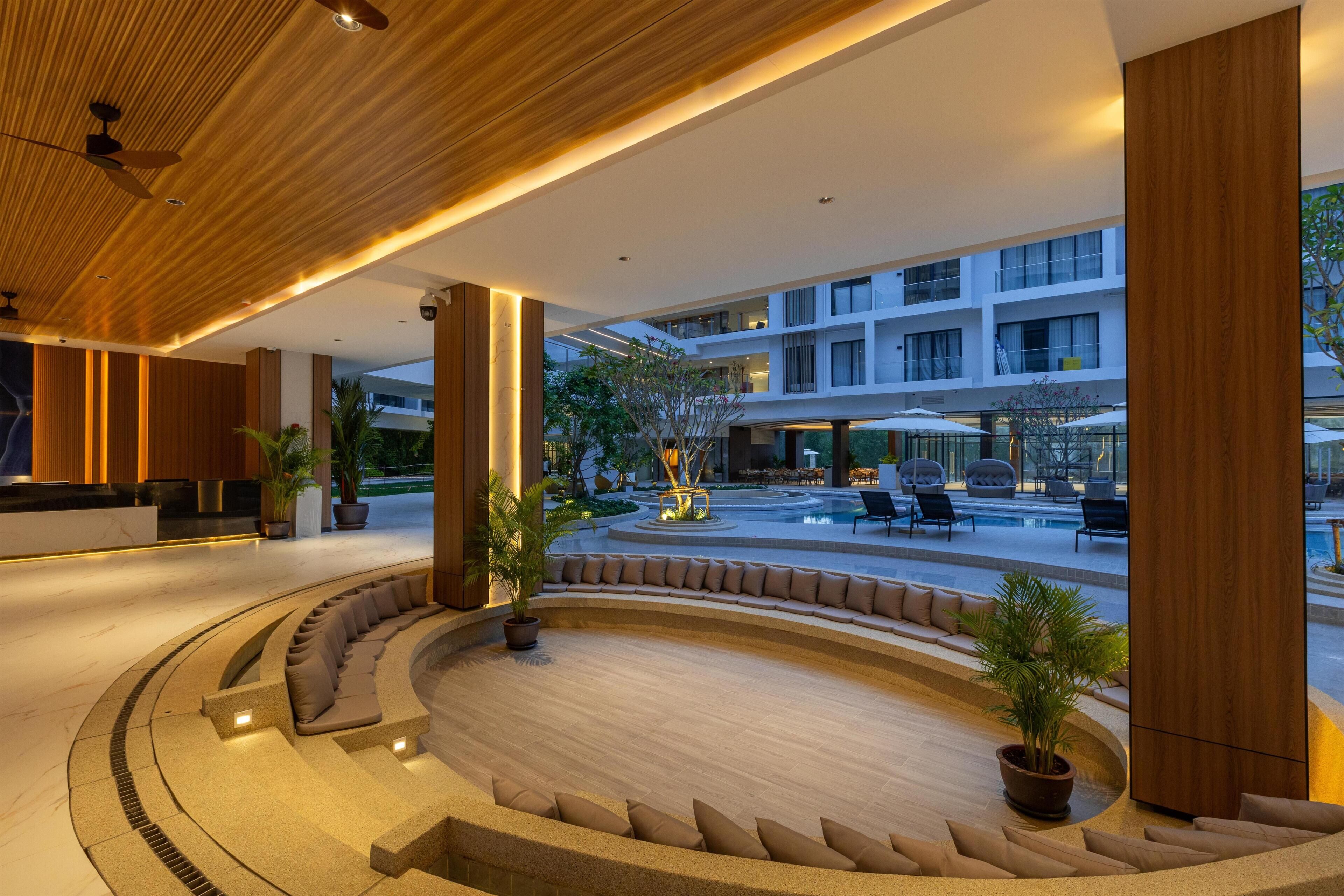Un moderno vestíbulo de hotel con un área de estar central, una piscina y vistas del exterior del edificio.
