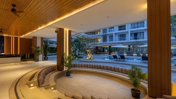 Un moderno vestíbulo de hotel con un área de estar central, una piscina y vistas del exterior del edificio.
