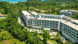 A modern hotel complex with multiple buildings, surrounded by lush greenery and a view of the sea. - Radisson Resort Layan Phuket (Choeng Thale)