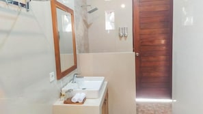 A bathroom with a sink, mirror, and shower.