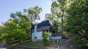 A modern house with a sloped roof, a small porch, and a staircase leading to the entrance. - Seabright Sanctuary - COMFY beds - mins from Margaritaville! (Osage Beach)