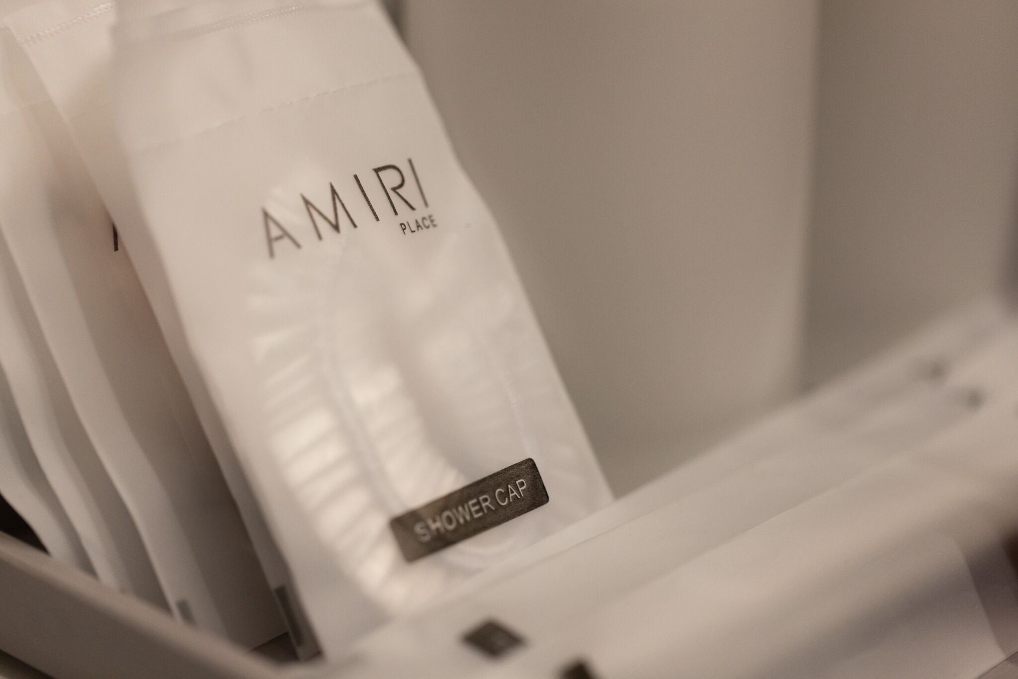 Un baño blanco con un gorro de ducha con la etiqueta 'AMIR PLACE' y un gorro de ducha con la etiqueta 'SHOWER CAP'.