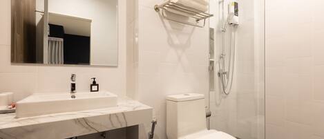A modern bathroom with a marble sink, a toilet, a glass shower enclosure, and a towel rack.