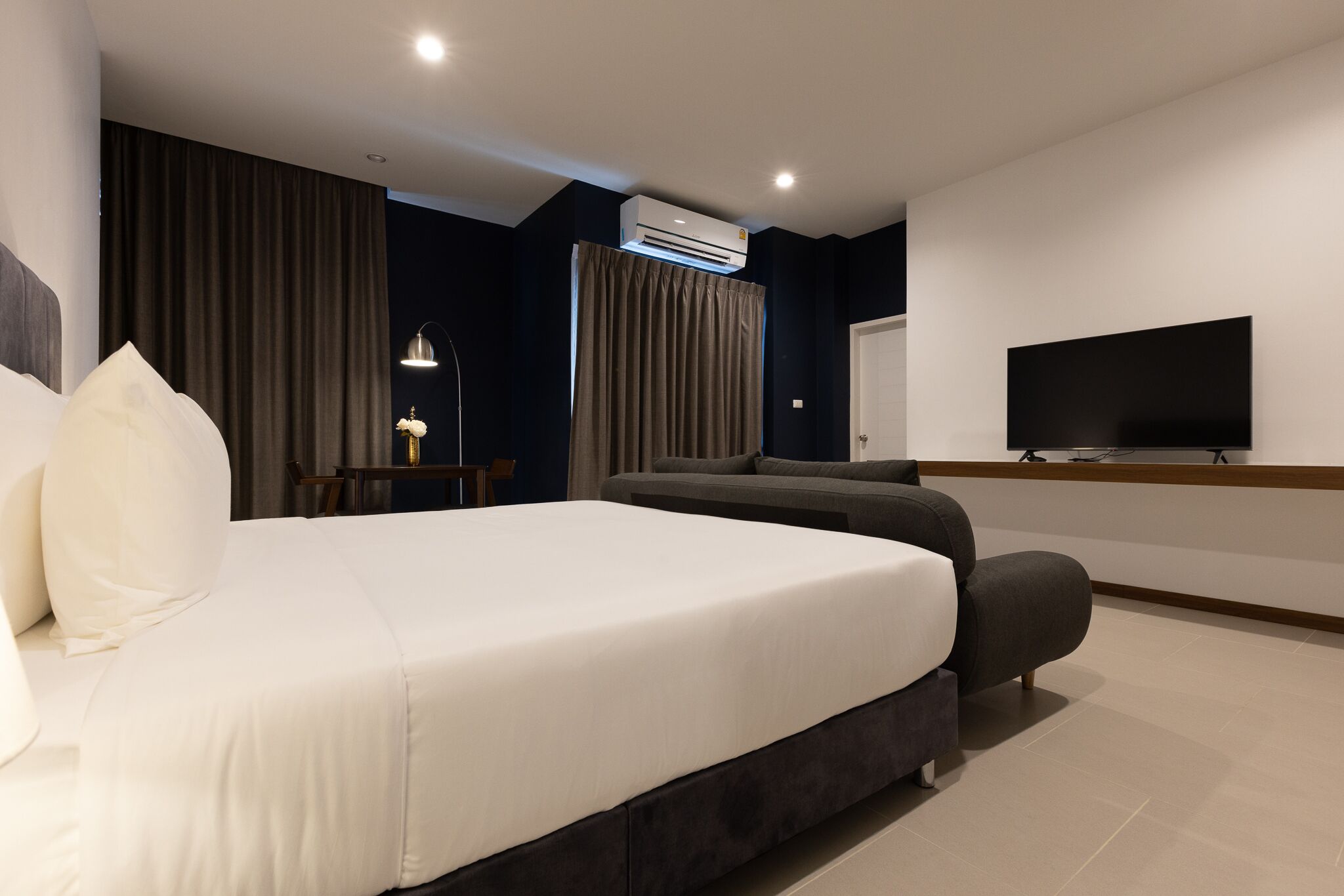 Une chambre d’hôtel moderne équipée d’un grand lit, d’un canapé, d’un téléviseur à écran plat et d’un système de climatisation.