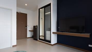A modern living room with a flat-screen TV mounted on a dark wall, a sliding glass door, and a wooden door.