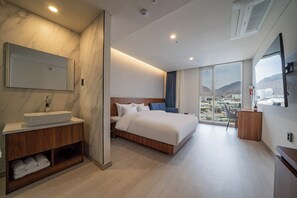 A modern hotel room with a large bed, a built-in vanity with a sink, a large window offering a city view, and a flat-screen TV mounted on the wall. - Orayeon Hotel Yeongwol (Yeongwol)