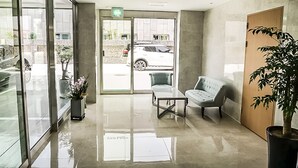 A modern lobby with a glass entrance, a seating area with a sofa and armchairs, and a potted plant. - Orayeon Hotel Yeongwol (Yeongwol)
