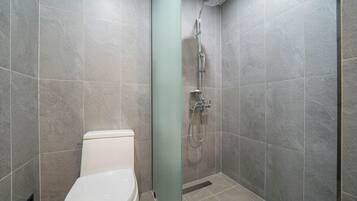 A modern bathroom with a shower, toilet, and a glass partition.