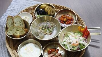 A wooden table with a woven tray holding various dishes including bread, salad, and soup.