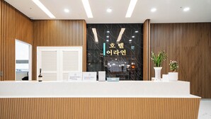A reception desk with a wooden panel design, a black marble wall with Korean text, and a potted plant. - Orayeon Hotel Yeongwol (Yeongwol)