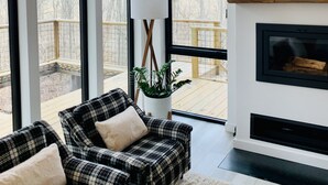 A modern living room with large windows, a fireplace, and a cozy seating area. - Anjuna River House - the hidden Scandi cabin on 12 acres in Southern Indiana!  (New Pekin)