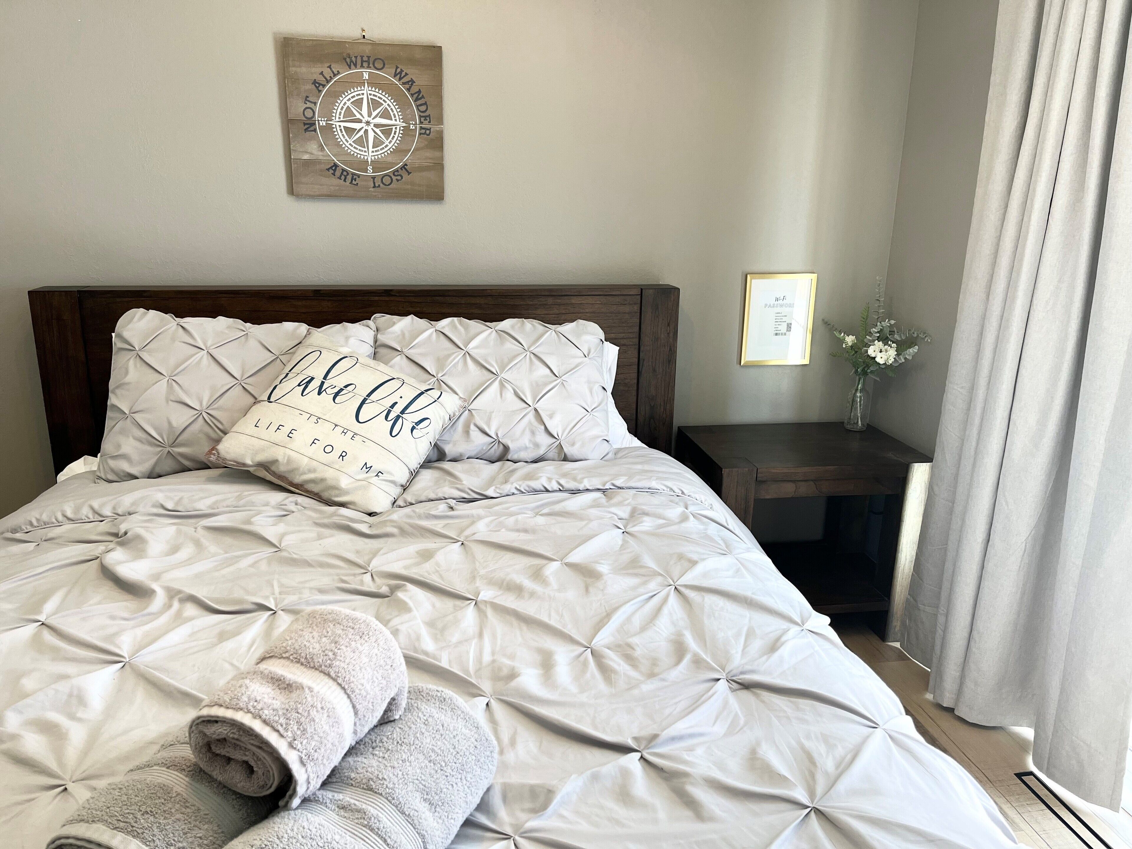 A neatly made bed with a pillow that reads "Life is the journey, not the destination."