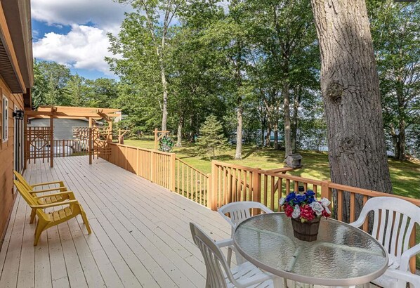 A wooden deck with outdoor seating and a view of a forest.