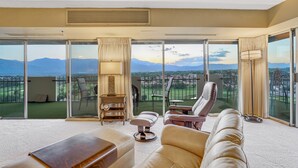 Un vaste salon doté d’une grande porte-fenêtre coulissante donnant sur un balcon avec vue sur les montagnes.
